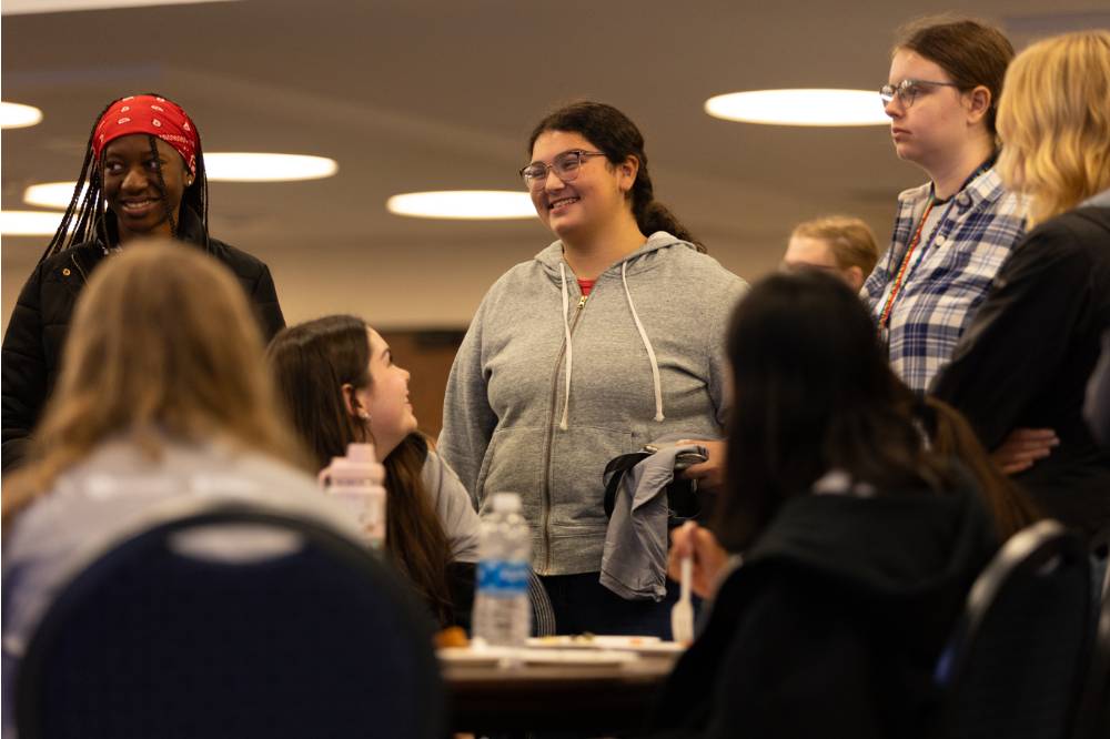 A student smiles while chatting with other students